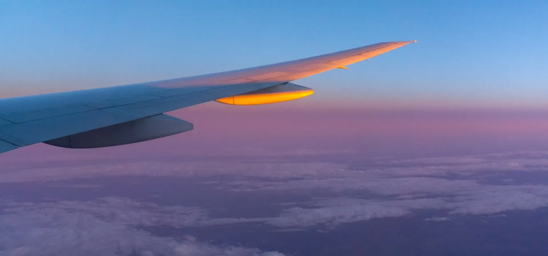 L'aile d'un avion en plein vol au coucher du soleil au-dessus des nuages.